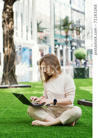 Woman using laptop outdoors Woman using laptop outdoors 71163268