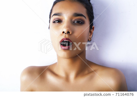 young pretty indian woman with dry fruit in mouth on white background 71164076