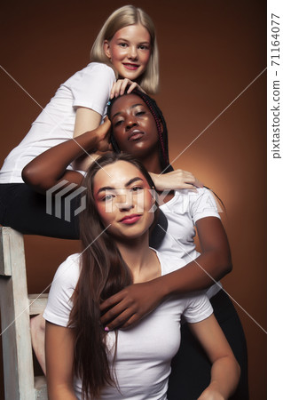 young pretty asian, caucasian, afro woman posing cheerful together on brown background, lifestyle diverse nationality people concept young pretty asian, caucasian, afro woman posing cheerful together on brown background, lifestyle diverse nationality people concept 71164077