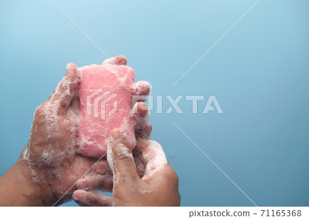 young man washing hands with soap warm water  71165368