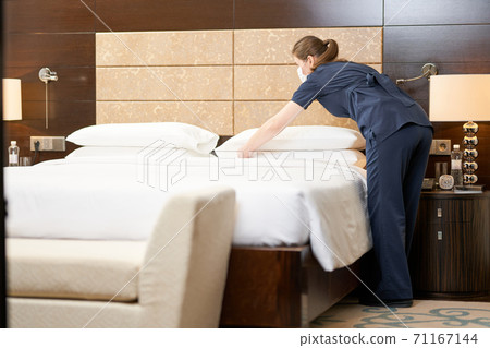Professional chambermaid cleaning a luxury hotel room 71167144