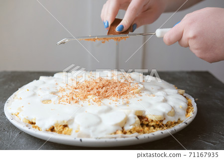 woman's hands grating chocolate on Banoffee pie 71167935