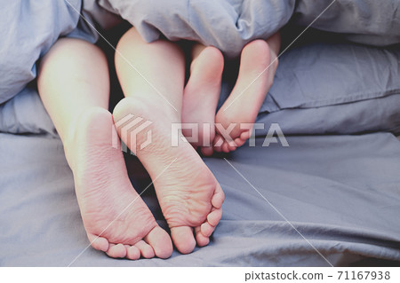Brother and little sister lying in the bed and showing feet. 71167938