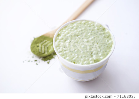 matcha latte in a cup and matcha powder in wooden spoon. 71168053