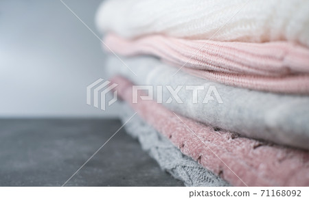 a pile of knitted sweaters in grey and pink colors. 71168092
