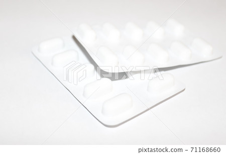 Pharmacy drugstore concept. Packs of white pills packed in blisters with copy space isolated on a white background. Focus on foreground, soft bokeh. Pharmacy drugstore concept. Packs of white pills packed in blisters with copy space isolated on a white background. Focus on foreground, soft bokeh. 71168660