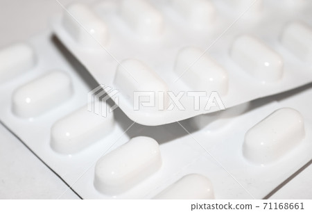Pharmacy drugstore concept. Packs of white pills packed in blisters with copy space isolated on a white background. Focus on foreground, soft bokeh. Pharmacy drugstore concept. Packs of white pills packed in blisters with copy space isolated on a white background. Focus on foreground, soft bokeh. 71168661