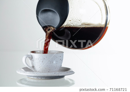 Coffee is poured from the coffee maker into a cup. Coffee is poured from the coffee maker into a cup. 71168721