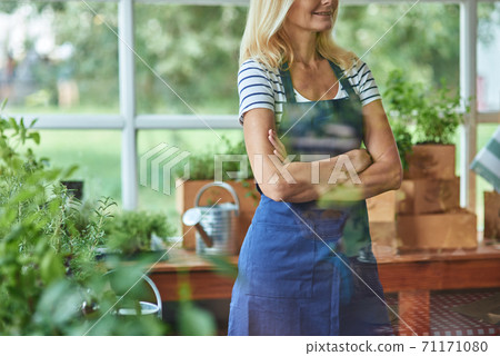 Woman in apron standing with crossed hands Woman in apron standing with crossed hands 71171080