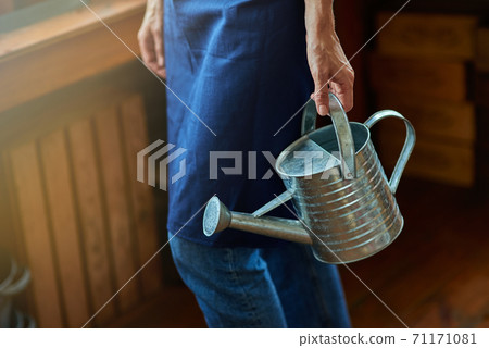 Selective focus on watering can in working woman hand Selective focus on watering can in working woman hand 71171081