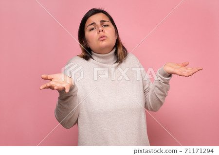 Beautiful caucasian doubtful woman shrugs her shoulders. Beautiful caucasian doubtful woman shrugs her shoulders. 71171294