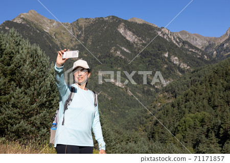 Young tourist woman take a picture from mountain with mobile phone Young tourist woman take a picture from mountain with mobile phone 71171857