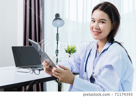 Woman doctor on front laptop computer hold modern tablet Woman doctor on front laptop computer hold modern tablet 71174393