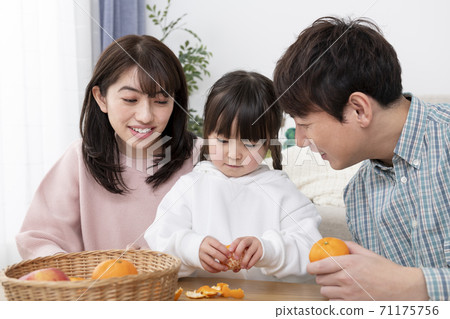 A girl peeling oranges and parents watching over her family image 71175756