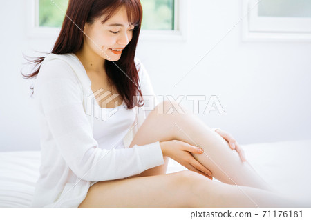 Woman doing leg skin care on the bed 71176181