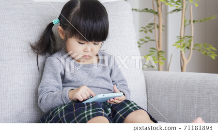 A child looking at a smartphone in the living room A child looking at a smartphone in the living room 71181893