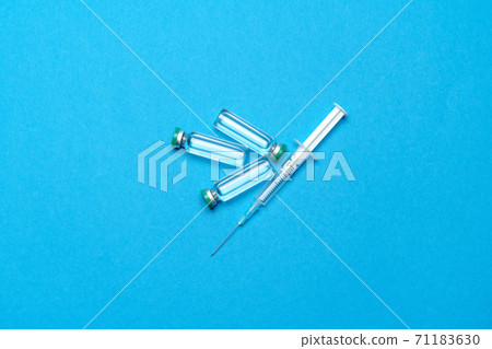 Syringe and ampoules with medicines or vaccine over blue background 71183630