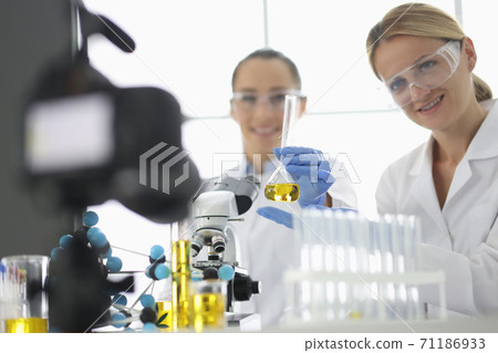 Two researchers are filming experiments in laboratory on camera 71186933