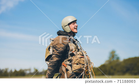 A man wearing a helmet. Man with parachute after landing. All in dirt and laughs 71188003