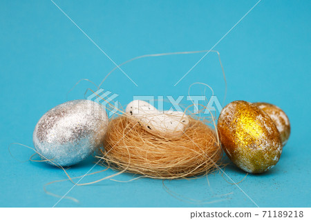 Gold and silver Easter eggs with nest on a blue background. Easter concept. Happy Easter. Copy space 71189218