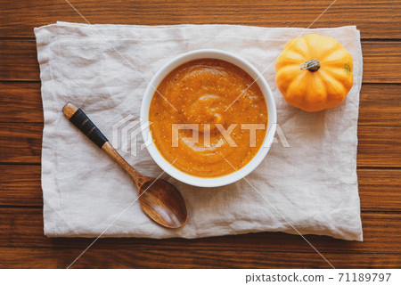Hot pumpkin soup in a bowl on wooden background, top view. Hot pumpkin soup in a bowl on wooden background, top view. 71189797