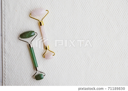 Jade stone roller made of pink quartz on white background. 71189830