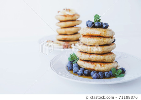 Stack of homemade small thick pancakes served with fresh blueberries. 71189876
