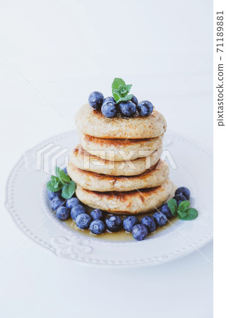 Stack of homemade small thick pancakes served with fresh blueberries. 71189881