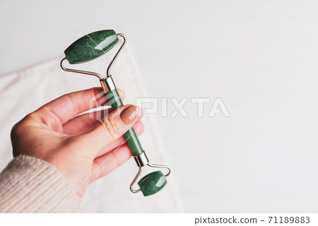 Jade stone roller made of pink quartz on white background. 71189883