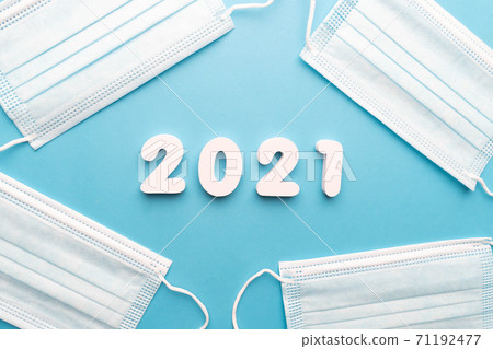 Protective medical face mask with 2021 number on blue background. Happy New Year for health care and medical banner/calendar cover. Protective medical face mask with 2021 number on blue background. Happy New Year for health care and medical banner/calendar cover. 71192477