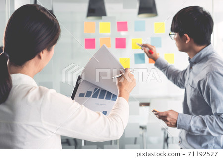 Business manager showing idea for her team and stick many memo paper on glass window to success working in business meeting  creative office, planning and management concept. 71192527