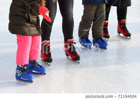 feet of different people skating on the ice rink feet of different people skating on the ice rink 71194084