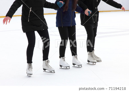 three girls holding hands ice-skating on the ice rink. three girls holding hands ice-skating on the ice rink. 71194218