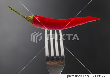 Red hot pepper with fork close-up on dark background. Healthy vegetable food and vitamins Red hot pepper with fork close-up on dark background. Healthy vegetable food and vitamins 71194275