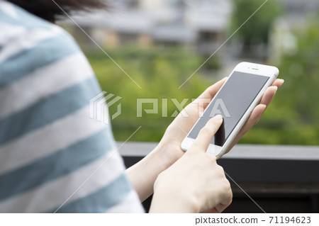 Woman operating a smartphone outdoors 71194623