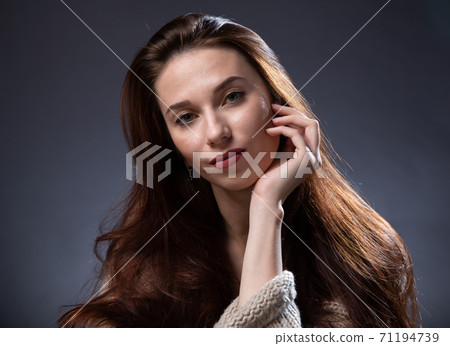 Image of woman with long hair and hand on chin on dark background Image of woman with long hair and hand on chin on dark background 71194739