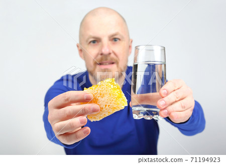 the man offers to eat comb honey and a glass of water. Healthy diet the man offers to eat comb honey and a glass of water. Healthy diet 71194923