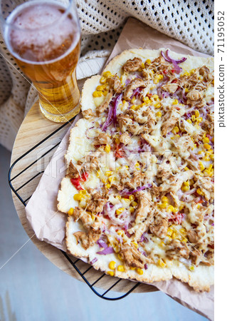 A glass of cold light beer. Very tasty and appetizing pizza with ham, red onion, corn, cheese. Thin Italian pastry. Close-up, top view. A glass of cold light beer. Very tasty and appetizing pizza with ham, red onion, corn, cheese. Thin Italian pastry. Close-up, top view. 71195052