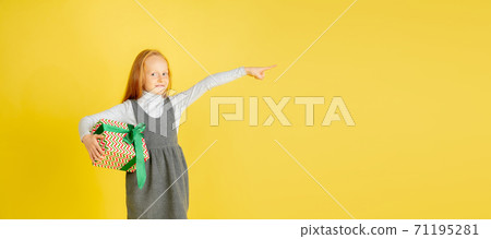 Giving and getting presents on Christmas holidays. Teen girl having fun isolated on yellow studio background 71195281