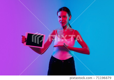 Young caucasian woman's portrait on gradient blue-purple studio background in neon light Young caucasian woman's portrait on gradient blue-purple studio background in neon light 71196879