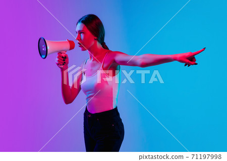 Young caucasian woman's portrait on gradient blue-purple studio background in neon light Young caucasian woman's portrait on gradient blue-purple studio background in neon light 71197998