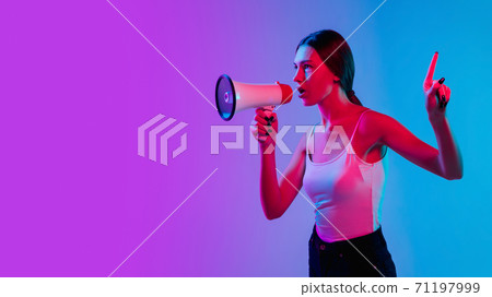 Young caucasian woman's portrait on gradient blue-purple studio background in neon light 71197999