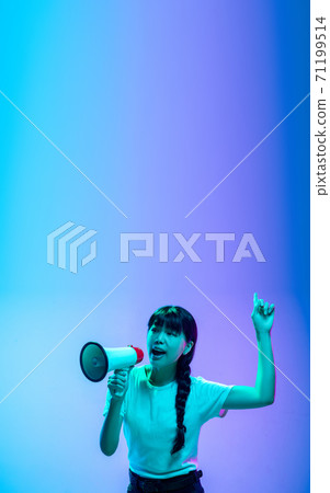 Young asian woman's portrait on gradient blue-purple studio background in neon light 71199514