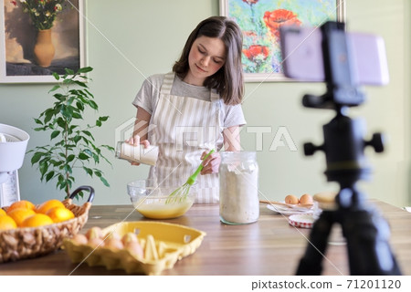 Girl teenager food blogger cooking orange pancakes at home in kitchen Girl teenager food blogger cooking orange pancakes at home in kitchen 71201120