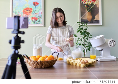 Girl teenager food blogger cooking orange pancakes at home in kitchen 71201144