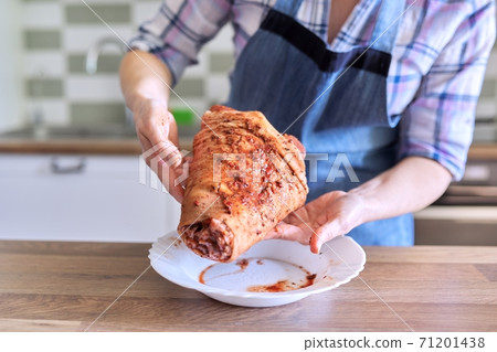 Female housewife in apron cooking meat at home in the kitchen Female housewife in apron cooking meat at home in the kitchen 71201438