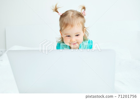 The child carefully looks into the laptop monitor 71201756
