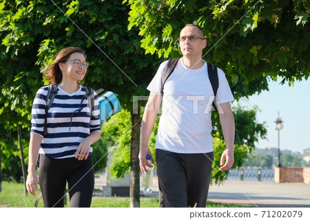 Outdoor walking man and woman, talking people, middle-aged couple Outdoor walking man and woman, talking people, middle-aged couple 71202079