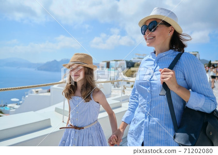 Mother walking with daughter child in famous tourist village Oia Santorini 71202080