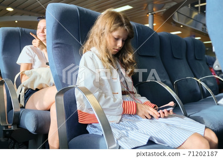 Girl child using smartphone while sitting inside ferry Girl child using smartphone while sitting inside ferry 71202187